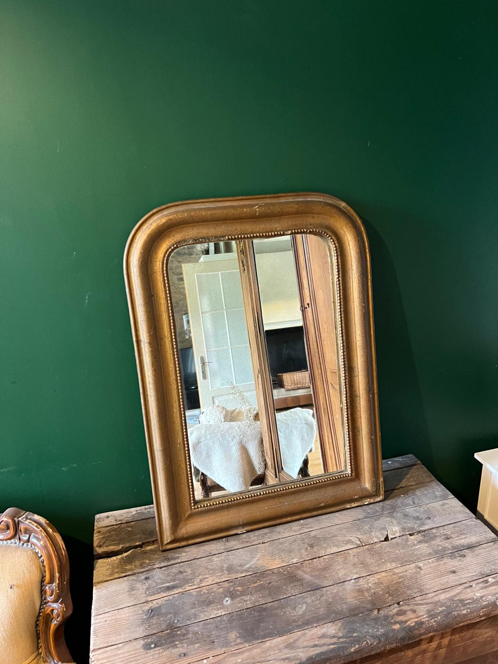 La Ferme Anglaise antique French Louis Philippe gilt mirror with a beaded border and foxed glass on a wooden surface.