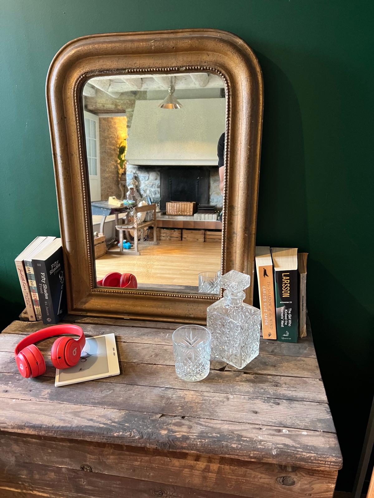 La Ferme Anglaise antique French Louis Philippe gilt mirror with beaded border and foxed glass on a wooden table.