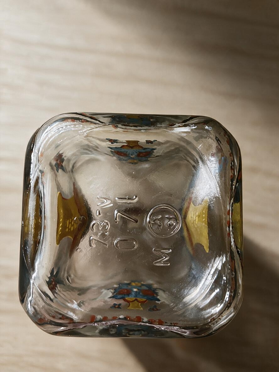 Base of a vintage La Ferme Anglaise enamelled glass liqueur decanter showing embossed markings and folk art details