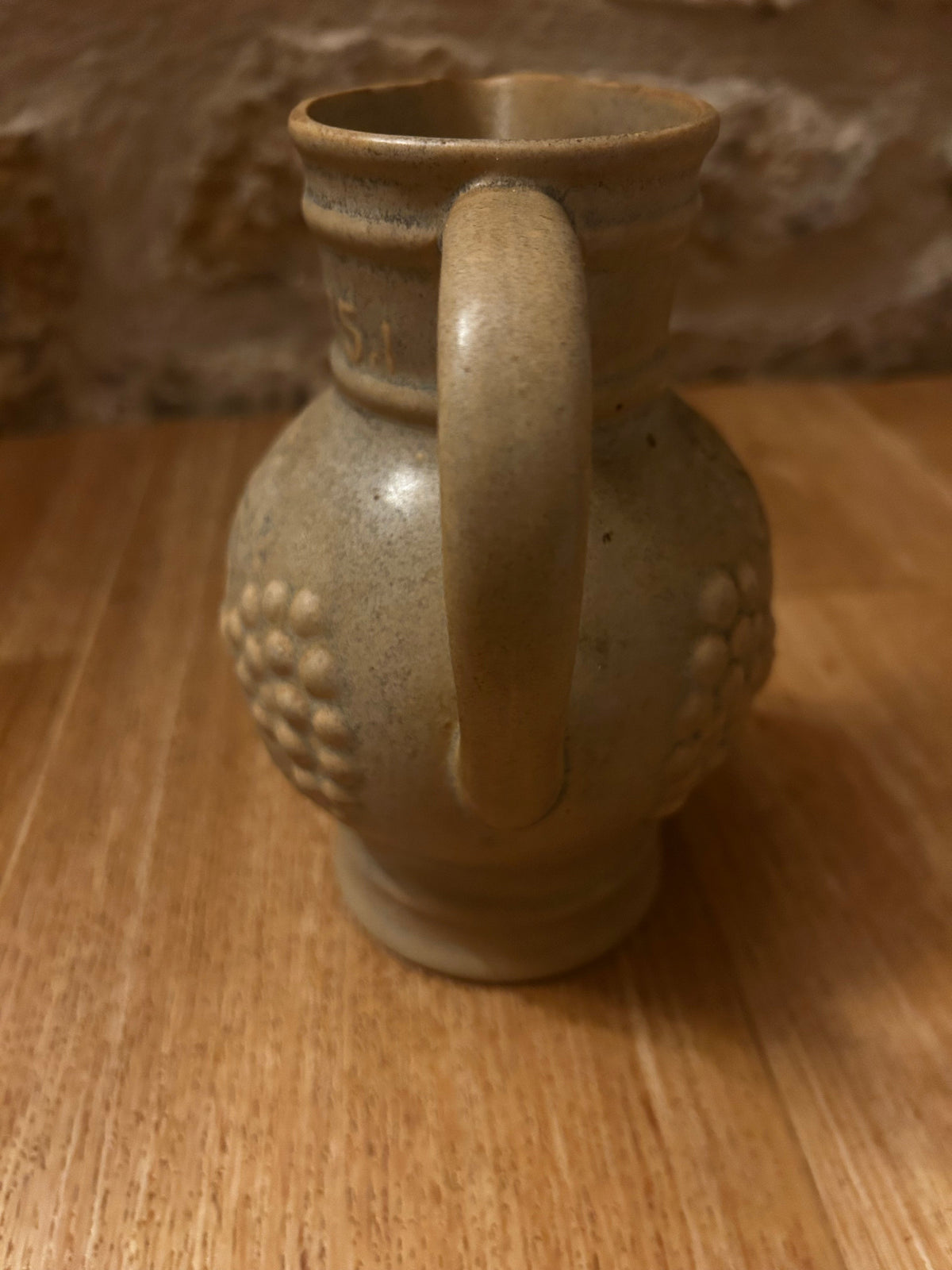 La Ferme Anglaise vintage French stoneware wine jug in speckled grey-beige with embossed grape and vine relief detail.