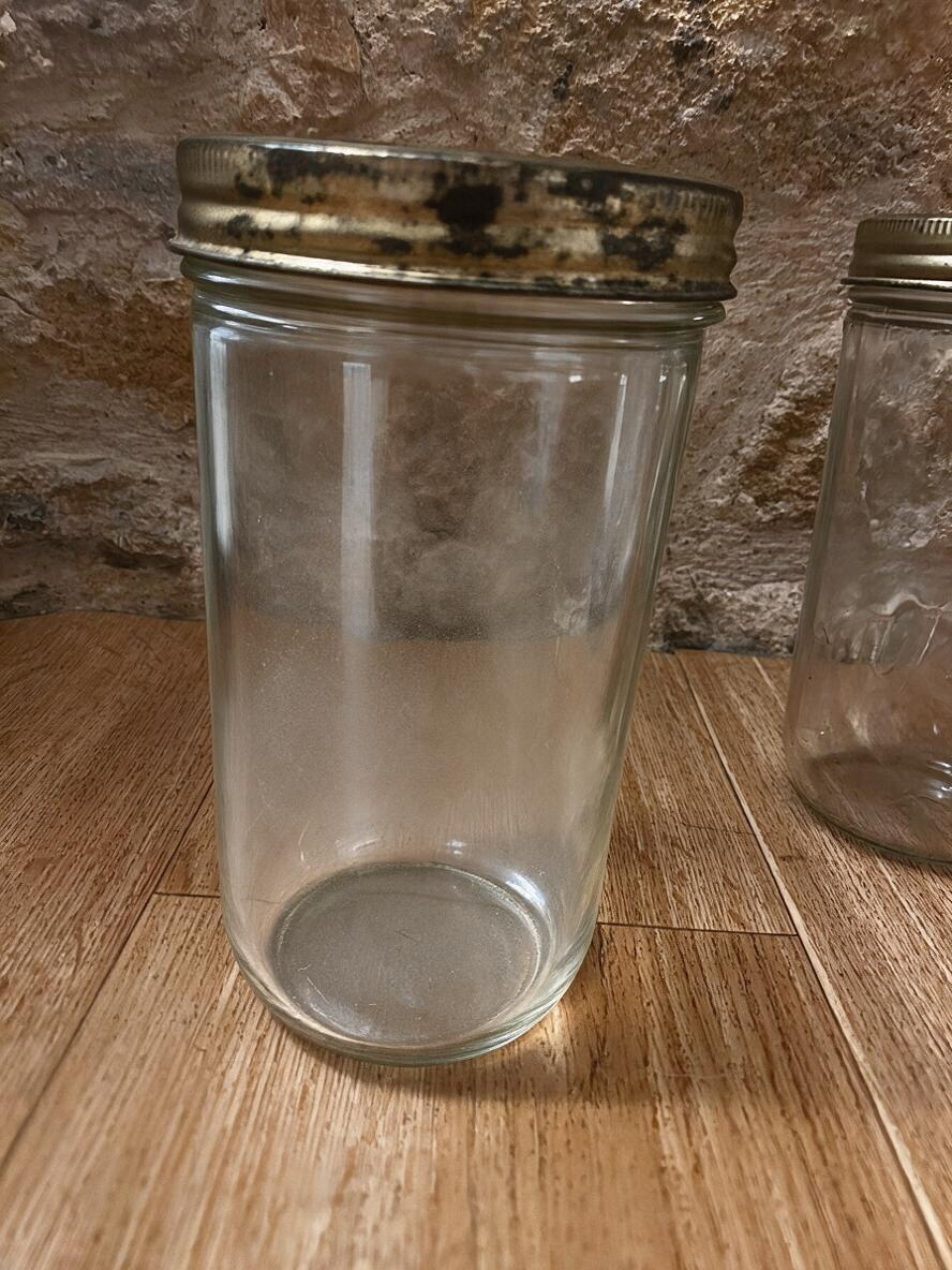 La Ferme Anglaise vintage French glass storage jar with a tarnished gold-tone metal screw lid on a wooden surface.